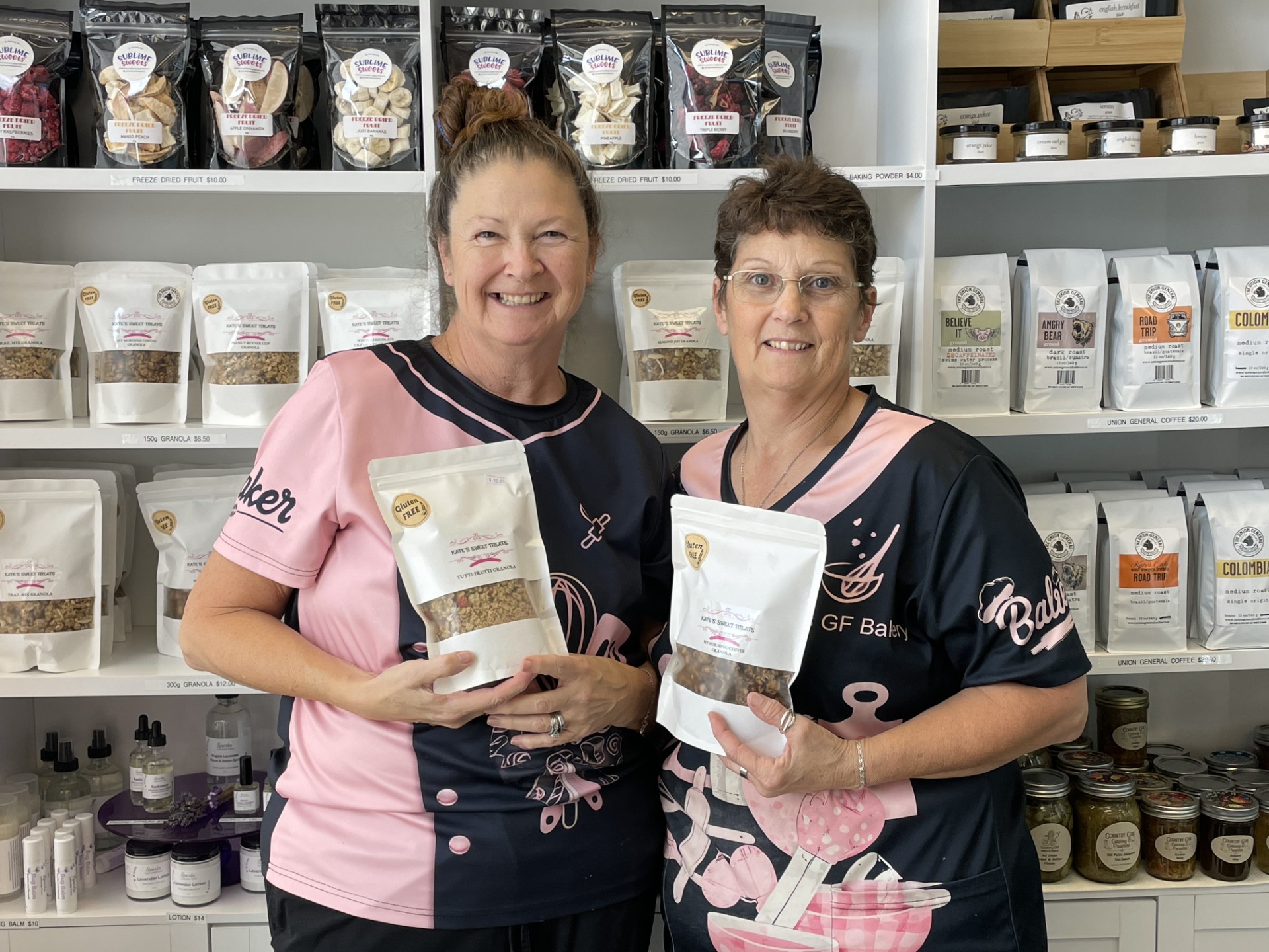 Kate and her partner holding bags of Kate's granola in the shop